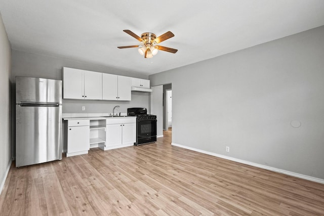 701 W Hull St Unit 101-2, Denison, TX 75020 - kitchen with freestanding refrigerator, black gas stove, a ceiling fan, white cabinets, and light wood finished floors