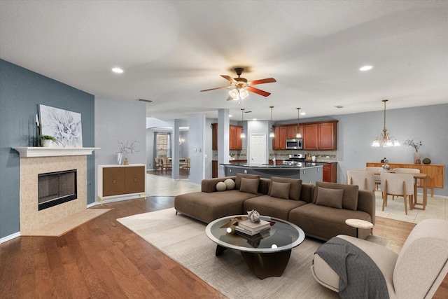 9324 Shadowfax Dr, Arlington, TX 76002 - living room featuring wood finished floors, a tile fireplace, a ceiling fan, a chandelier, and recessed lighting