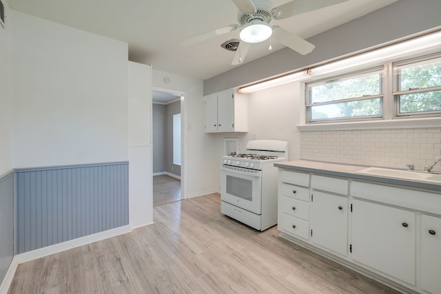 2442 Oates Dr, Dallas, TX 75228 - kitchen featuring gas range gas stove, light wood-style flooring, backsplash, white cabinetry, and plenty of natural light