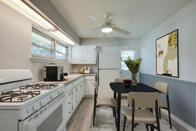 2442 Oates Dr, Dallas, TX 75228 - kitchen with white appliances, light wood-style floors, healthy amount of natural light, a wainscoted wall, and white cabinetry