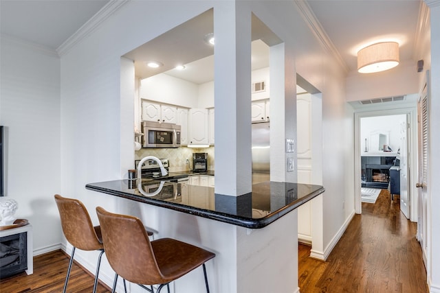 3208 Cole Ave Unit 1110, Dallas, TX 75204 - kitchen featuring stainless steel appliances, white cabinetry, crown molding, dark wood-type flooring, and backsplash