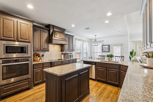 1344 Mountain View Ln, Kennedale, TX 76060 - kitchen featuring appliances with stainless steel finishes, custom exhaust hood, recessed lighting, light wood-style flooring, and tasteful backsplash