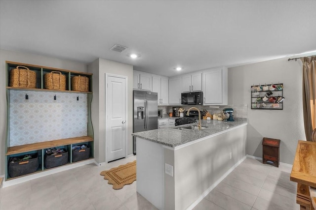 2525 Bunkerton Dr, Fort Worth, TX 76179 - kitchen with black microwave, range with gas cooktop, stainless steel fridge, a peninsula, and light stone counters