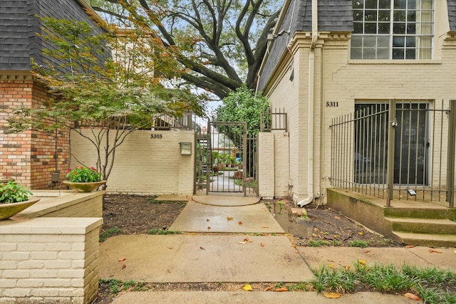 5305 Fleetwood Oaks Dr Unit 274, Dallas, TX 75235 - view of side of home featuring a gate, brick siding, mansard roof, and roof with shingles