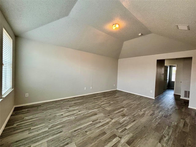 150 Wandering Dr, Forney, TX 75126 - empty room with a textured ceiling, dark wood finished floors, and vaulted ceiling