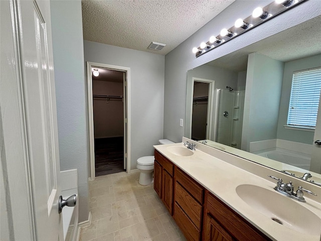 150 Wandering Dr, Forney, TX 75126 - bathroom featuring a textured ceiling, a spacious closet, a stall shower, double vanity, and a garden tub