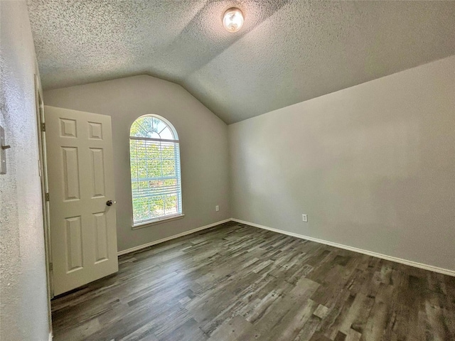 150 Wandering Dr, Forney, TX 75126 - empty room with dark wood-type flooring, vaulted ceiling, and a textured ceiling