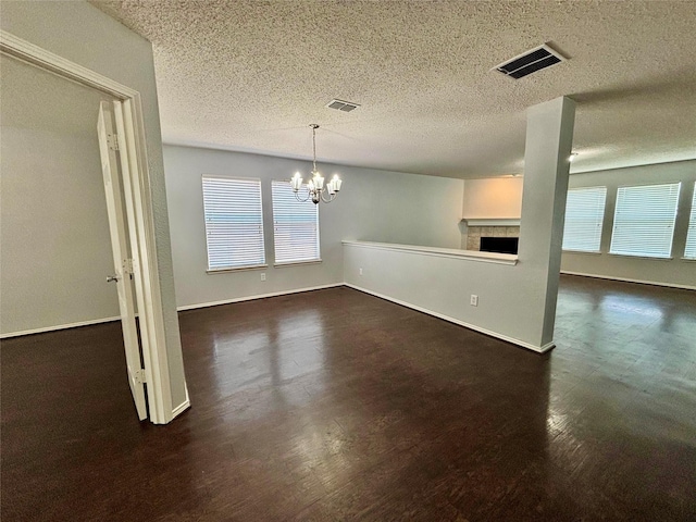 150 Wandering Dr, Forney, TX 75126 - unfurnished dining area featuring a chandelier, a tile fireplace, plenty of natural light, a textured ceiling, and dark wood-style flooring