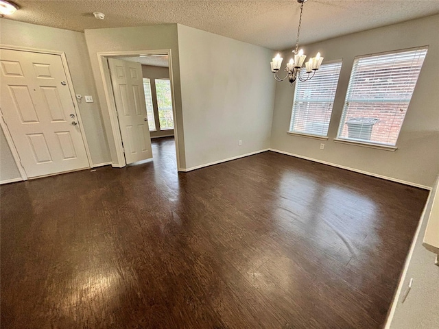 150 Wandering Dr, Forney, TX 75126 - empty room with dark wood finished floors, a textured ceiling, a chandelier, and a smoke detector