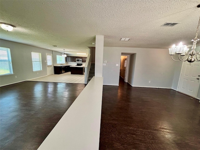 150 Wandering Dr, Forney, TX 75126 - unfurnished living room with a chandelier, a textured ceiling, and stairs