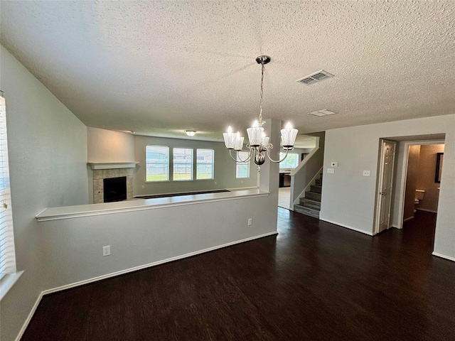 150 Wandering Dr, Forney, TX 75126 - unfurnished dining area featuring a chandelier, wood finished floors, a textured ceiling, a tiled fireplace, and stairs