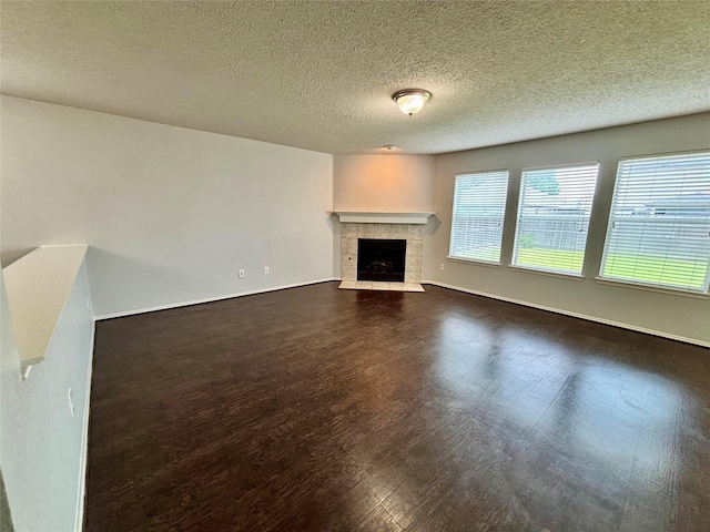 150 Wandering Dr, Forney, TX 75126 - unfurnished living room with a tile fireplace, dark wood-type flooring, and a textured ceiling