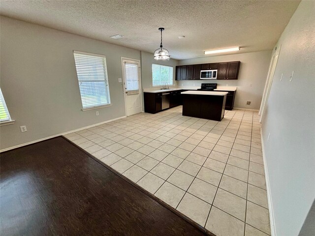 150 Wandering Dr, Forney, TX 75126 - kitchen featuring a kitchen island, light countertops, dark brown cabinets, hanging light fixtures, and light tile patterned flooring