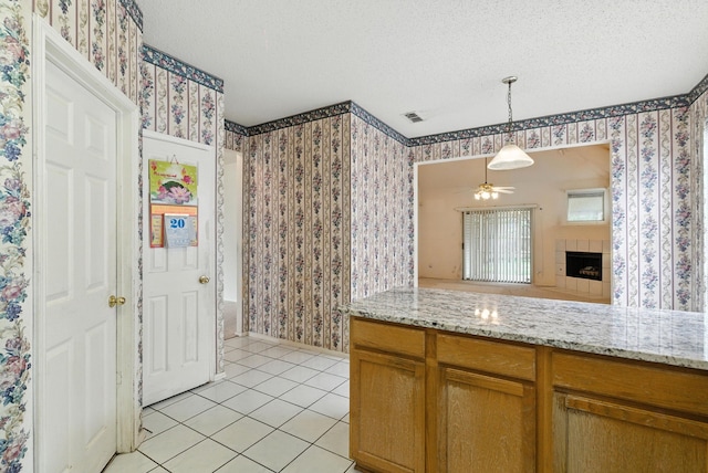 5004 Lodgepole Ln, Fort Worth, TX 76137 - kitchen with light tile patterned floors, wallpapered walls, a fireplace, a textured ceiling, and pendant lighting