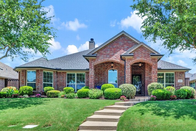1402 White Water Ln, Rockwall, TX 75087 - view of front of house with brick siding, a chimney, a shingled roof, and a front yard