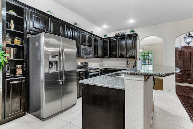 1402 White Water Ln, Rockwall, TX 75087 - kitchen with stainless steel appliances, arched walkways, light tile patterned floors, light stone counters, and backsplash