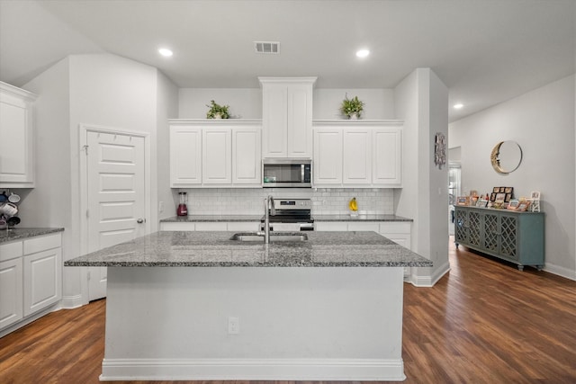 101 Paytons Way, Corsicana, TX 75110 - kitchen featuring appliances with stainless steel finishes, dark wood-type flooring, tasteful backsplash, white cabinets, and dark stone counters