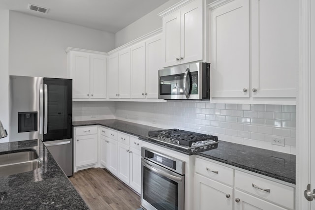 4919 Elizabeth Way, Lone Oak, TX 75453 - kitchen with appliances with stainless steel finishes, white cabinetry, wood finished floors, and backsplash
