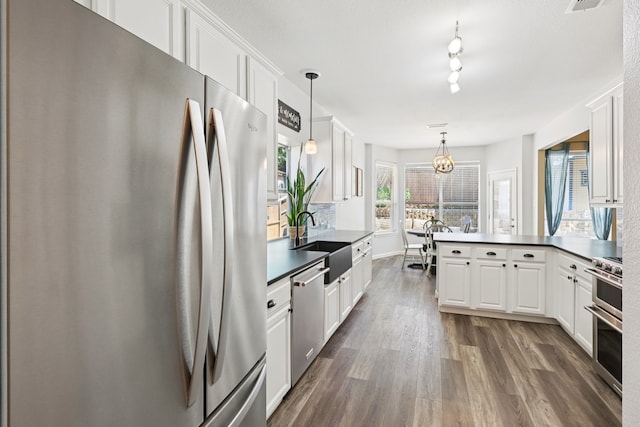 104 Northfield Cir, Hickory Creek, TX 75065 - kitchen featuring appliances with stainless steel finishes, a peninsula, dark wood finished floors, and white cabinets