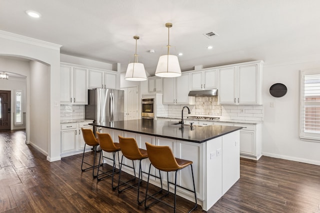 7716 Glenoaks Dr, Frisco, TX 75034 - kitchen featuring under cabinet range hood, dark wood-style flooring, stainless steel appliances, tasteful backsplash, and crown molding