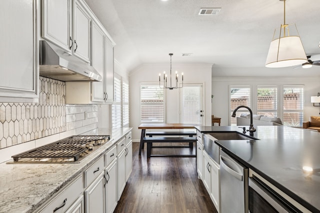 7716 Glenoaks Dr, Frisco, TX 75034 - kitchen with under cabinet range hood, appliances with stainless steel finishes, tasteful backsplash, open floor plan, and dark wood-style floors