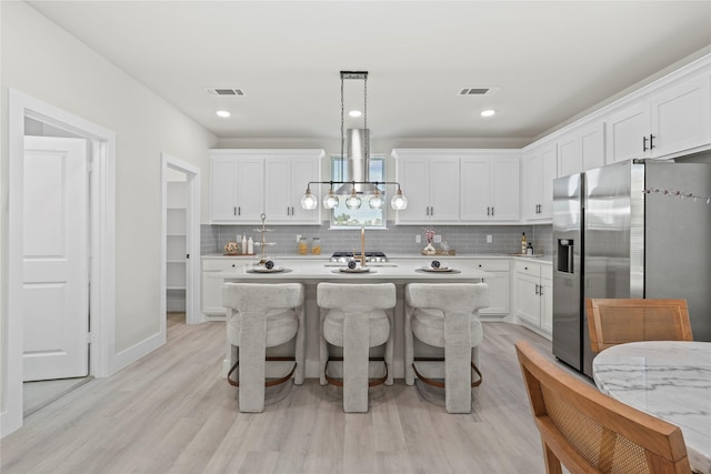5115 Hohen Ave, Dallas, TX 75215 - kitchen with stainless steel refrigerator with ice dispenser, light countertops, light wood finished floors, and white cabinets