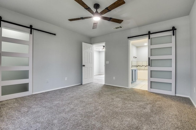 1004 Brae Loch Dr, Dallas, TX 75217 - unfurnished bedroom with a barn door, carpet floors, connected bathroom, and a ceiling fan