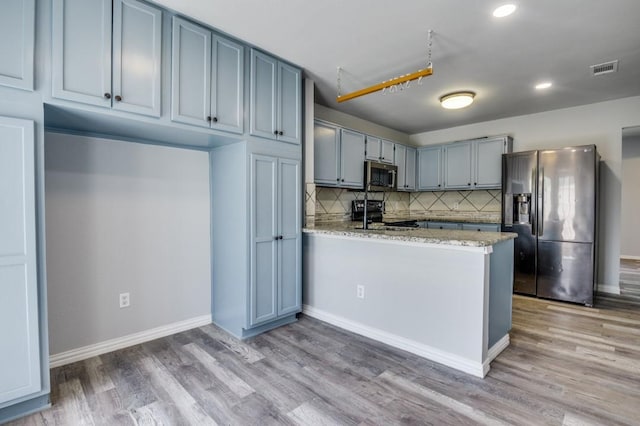 1004 Brae Loch Dr, Dallas, TX 75217 - kitchen featuring appliances with stainless steel finishes, a peninsula, decorative backsplash, light wood finished floors, and recessed lighting