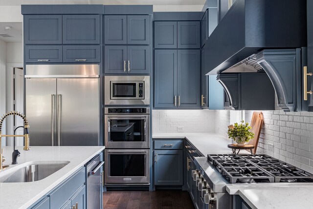8990 Frostweed Rd, Frisco, TX 75035 - kitchen featuring built in appliances, wall chimney exhaust hood, dark wood-type flooring, and light stone countertops