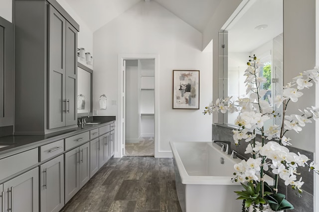 8990 Frostweed Rd, Frisco, TX 75035 - full bathroom with a soaking tub, wood finished floors, vanity, vaulted ceiling, and a closet