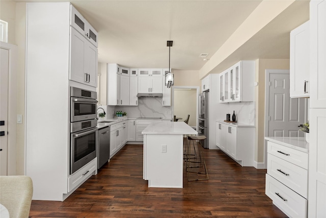 2124 Sandell Dr, Grapevine, TX 76051 - kitchen featuring appliances with stainless steel finishes, a kitchen bar, a center island, decorative backsplash, and light countertops