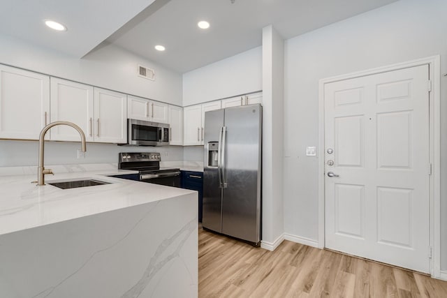 3102 Kings Rd Unit 2104, Dallas, TX 75219 - kitchen with appliances with stainless steel finishes, light stone countertops, light wood finished floors, white cabinetry, and recessed lighting