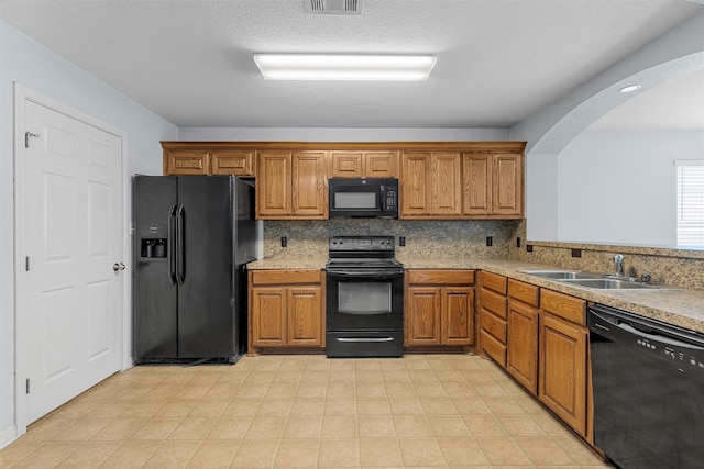 708 Sapphire Blvd, Hewitt, TX 76643 - kitchen with black appliances, brown cabinetry, arched walkways, light countertops, and decorative backsplash