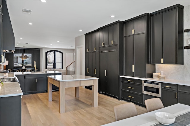 6716 Dalhart Ln, Dallas, TX 75214 - kitchen with dark cabinets, light wood-style flooring, recessed lighting, dishwasher, and a chandelier