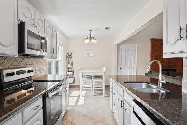7220 Elderberry Ln, Dallas, TX 75249 - kitchen featuring appliances with stainless steel finishes, tasteful backsplash, dark stone countertops, a chandelier, and white cabinetry