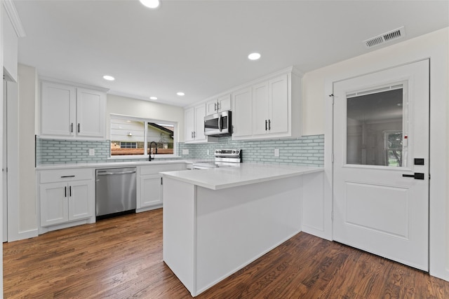 1315 Dunbarton Dr, Richardson, TX 75081 - kitchen featuring appliances with stainless steel finishes, white cabinets, tasteful backsplash, a peninsula, and light countertops
