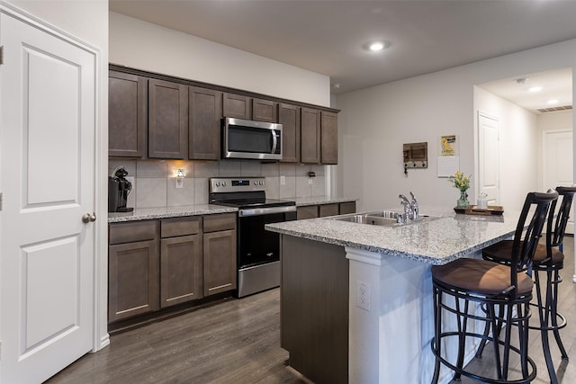 408 Cultivator Ct, Josephine, TX 75189 - kitchen with appliances with stainless steel finishes, decorative backsplash, a breakfast bar area, dark wood finished floors, and dark brown cabinets
