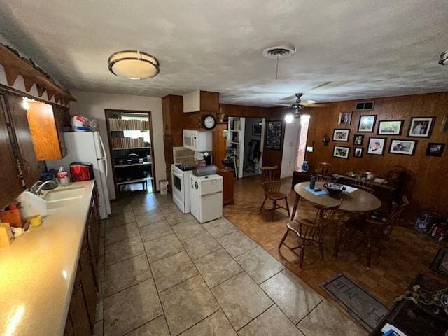 4411 Marigold Trl, Mesquite, TX 75150 - kitchen with white appliances, ceiling fan, light tile patterned floors, and wood walls