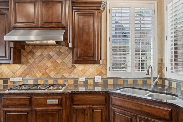 1316 Comal Dr, Allen, TX 75013 - kitchen featuring wall chimney range hood, stainless steel gas stovetop, decorative backsplash, and dark stone counters