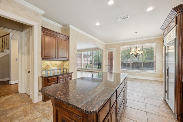 1316 Comal Dr, Allen, TX 75013 - kitchen with arched walkways, a chandelier, tasteful backsplash, decorative light fixtures, and crown molding