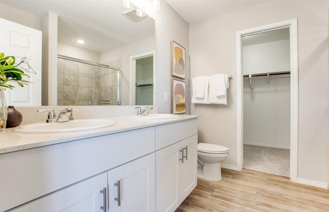 14159 Maida Dr, Pilot Point, TX 76258 - bathroom featuring a walk in closet, double vanity, a tile shower, wood finished floors, and recessed lighting