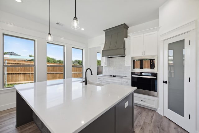 2700 NW 22nd St, Fort Worth, TX 76106 - kitchen with oven, custom exhaust hood, stainless steel microwave, light countertops, and decorative backsplash