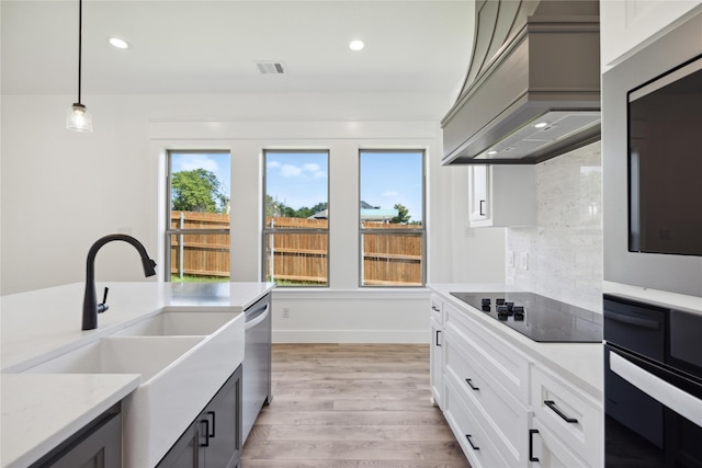 2700 NW 22nd St, Fort Worth, TX 76106 - kitchen with custom exhaust hood, black electric stovetop, wall oven, stainless steel dishwasher, and light wood finished floors