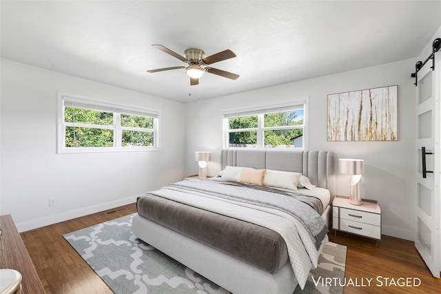 3501 Alta Vista Dr, Waco, TX 76706 - bedroom with a barn door, multiple windows, wood finished floors, and ceiling fan