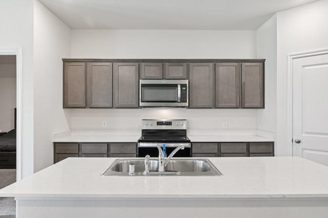288 Thoroughbred St, Waxahachie, TX 75165 - kitchen featuring stainless steel appliances, light countertops, a center island with sink, and dark brown cabinetry
