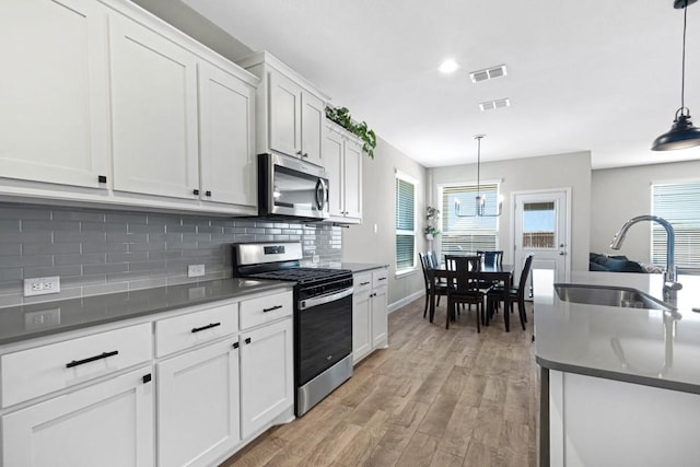 1160 Kirkham Way, Fort Worth, TX 76247 - kitchen with stainless steel appliances, dark countertops, light wood-style flooring, decorative backsplash, and white cabinetry