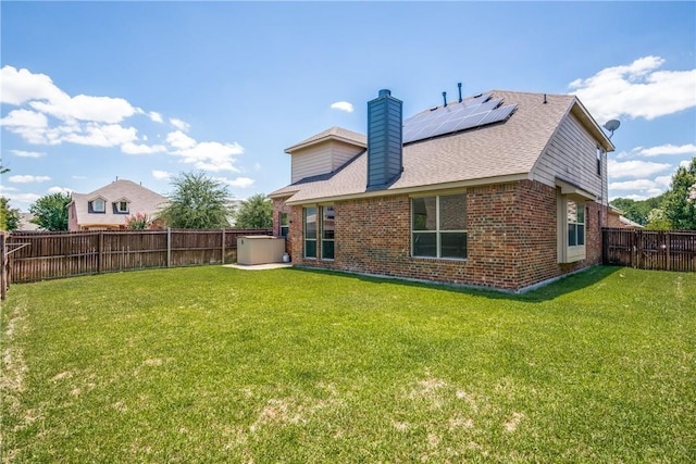 1300 Meadow Ranch Rd, Mckinney, TX 75071 - rear view of property with brick siding, a fenced backyard, roof mounted solar panels, a chimney, and a shingled roof