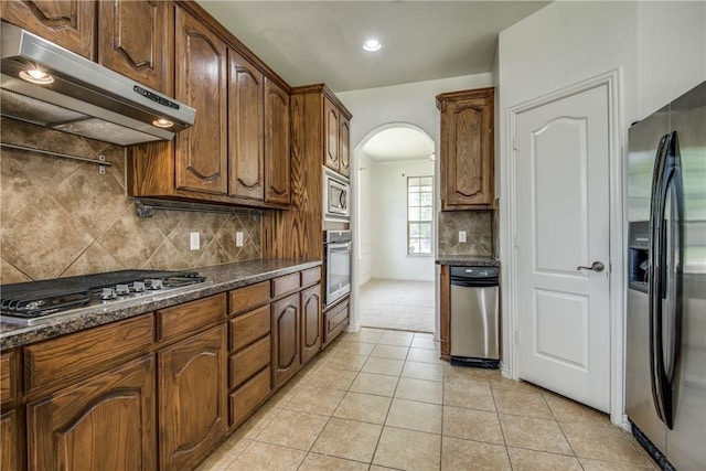 1300 Meadow Ranch Rd, Mckinney, TX 75071 - kitchen featuring stainless steel appliances, under cabinet range hood, arched walkways, tasteful backsplash, and light tile patterned floors