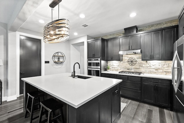 1521 Twistleaf Rd, Flower Mound, TX 76226 - kitchen with appliances with stainless steel finishes, wood finished floors, recessed lighting, backsplash, and an island with sink