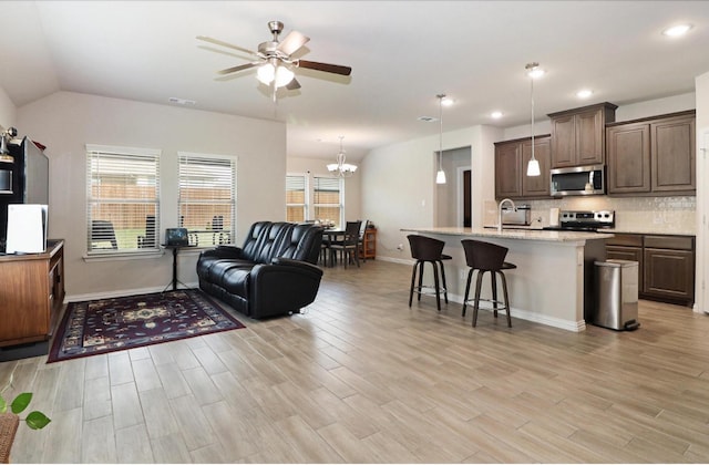505 Reatta Dr, Justin, TX 76247 - kitchen featuring stainless steel appliances, open floor plan, ceiling fan, light wood-type flooring, and a kitchen breakfast bar